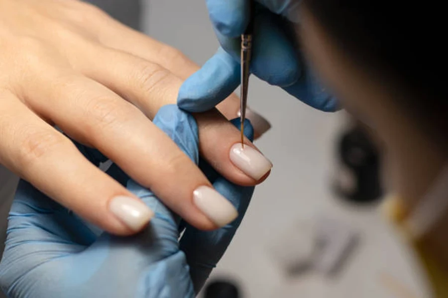 Woman getting nude nail art in tiny detail at salon