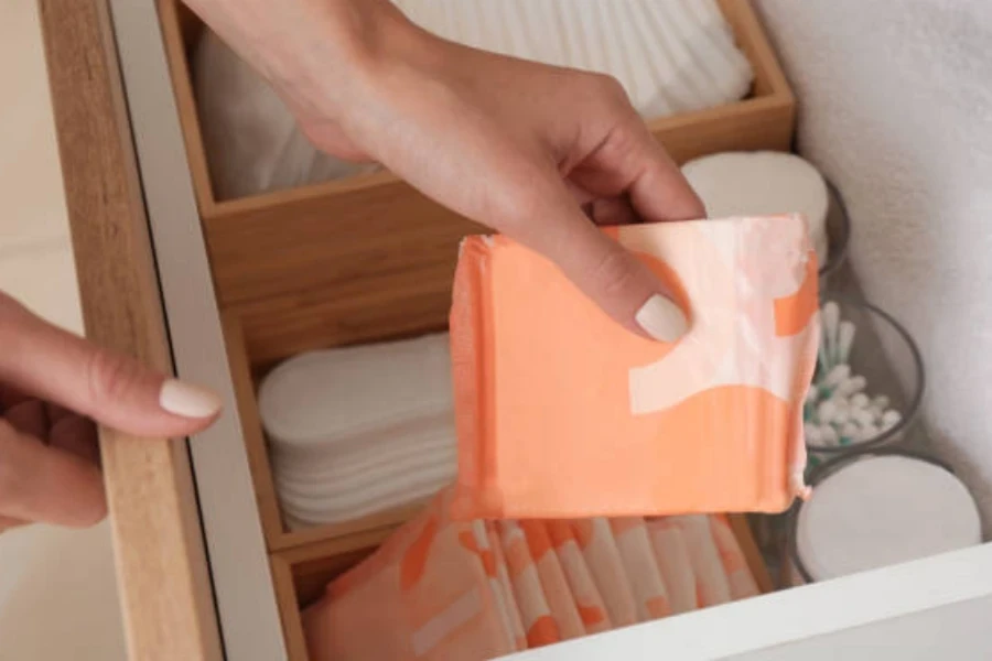 Woman taking disposable menstrual pad from drawer at home