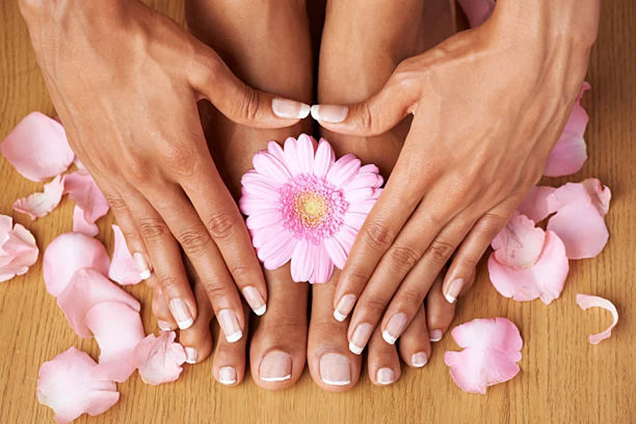 Woman wearing French manicure with pink flower petals on floor