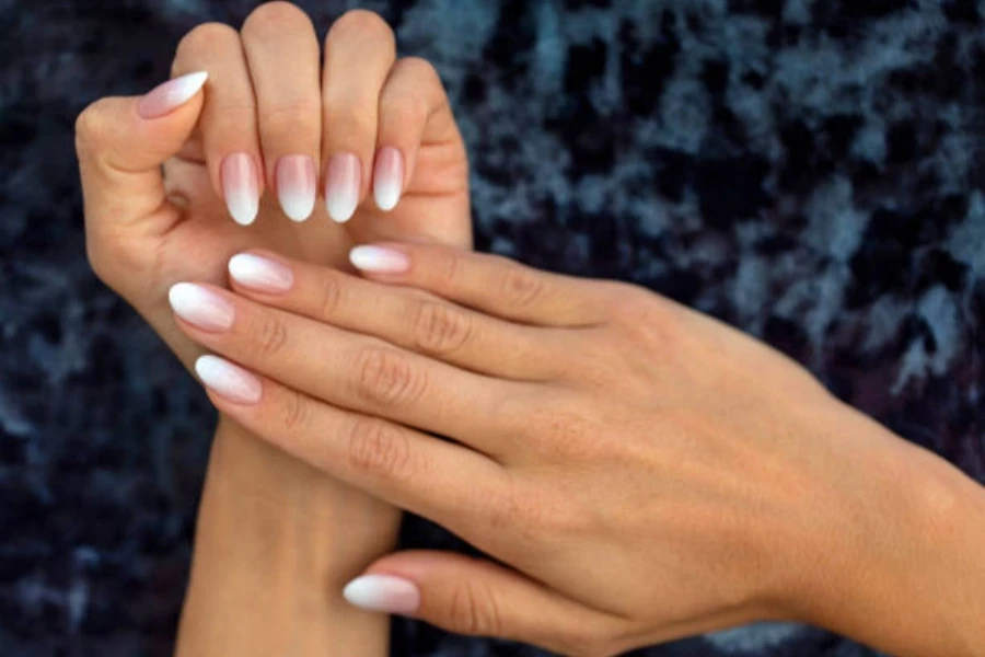 Woman wearing acrylic long nails with nude ombre tones