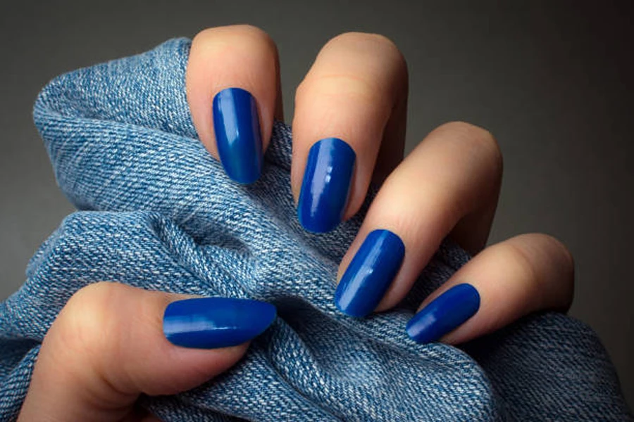 Woman wearing electric blue nail polish while holding material piece