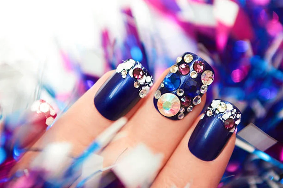 Woman wearing navy blue nails with gemstone embellishments