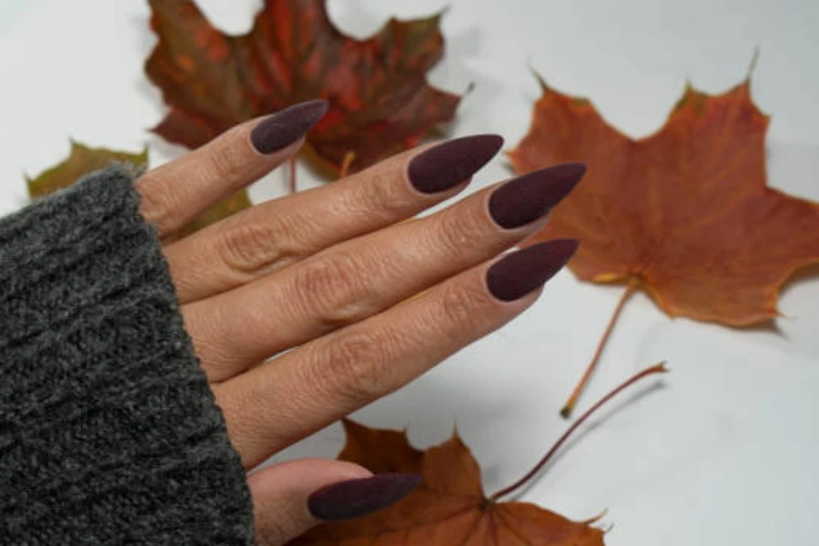 Woman wearing sweater with plum colored fall nails