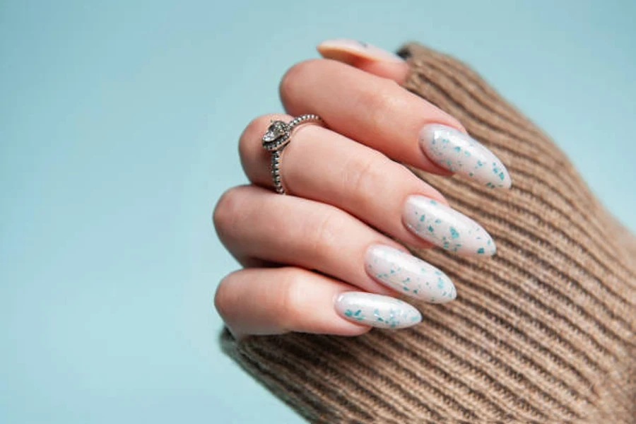 Woman wearing white artificial nails with blue speckles