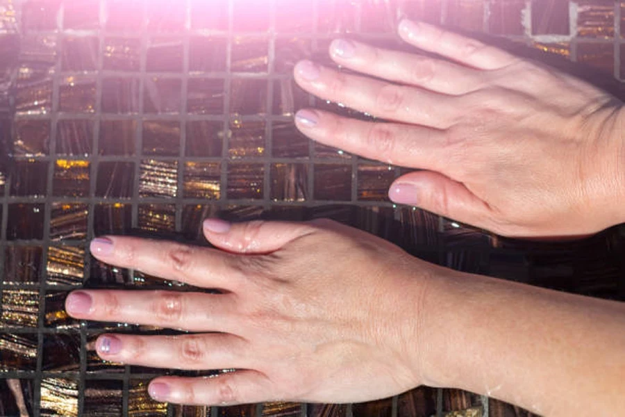 Woman with pink nude nails with glitter accents near cuticles