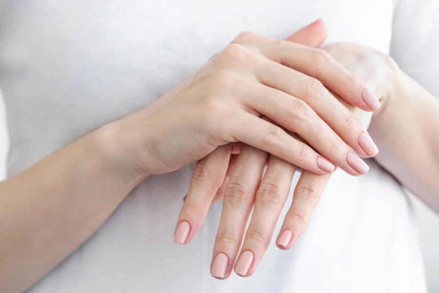 Woman with short nails painted in soft peach color