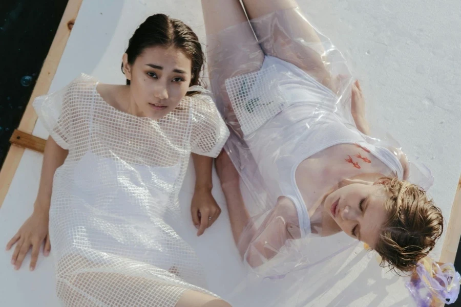 Women in Plastic Clothing Drifting on a Flat Board on a Body of Water