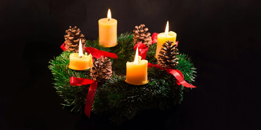 a group of lit candles sitting on top of a christmas wreath