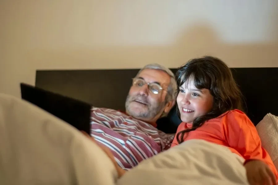 A man and a girl smiling while looking at a screen