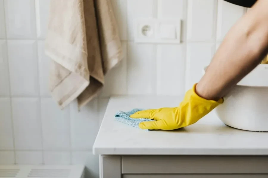 A person cleaning countertop with a kitchen towel