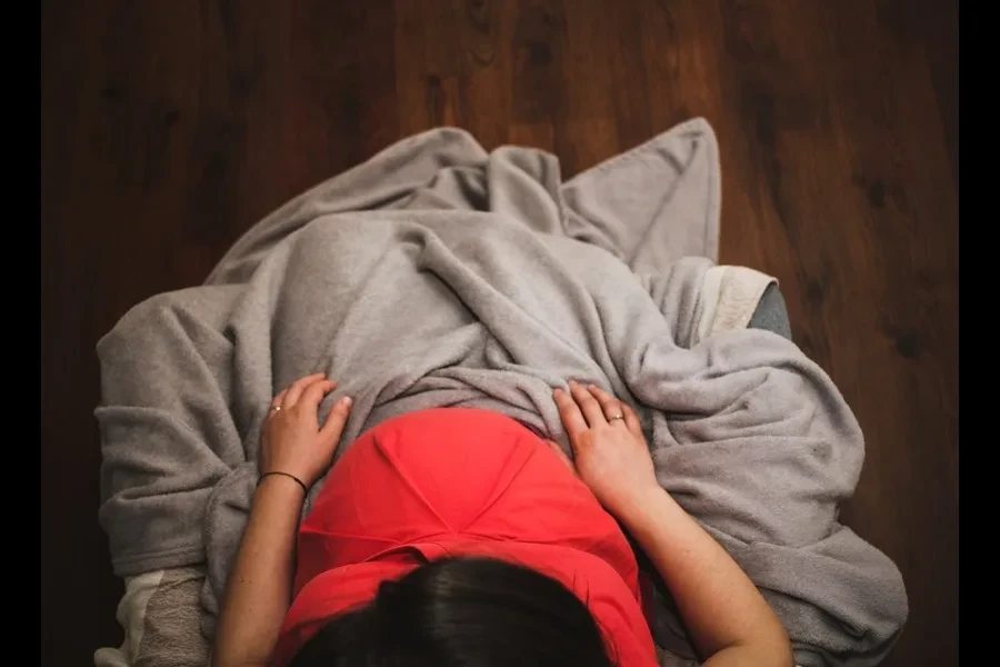 A pregnant lady sitting inside a quilt