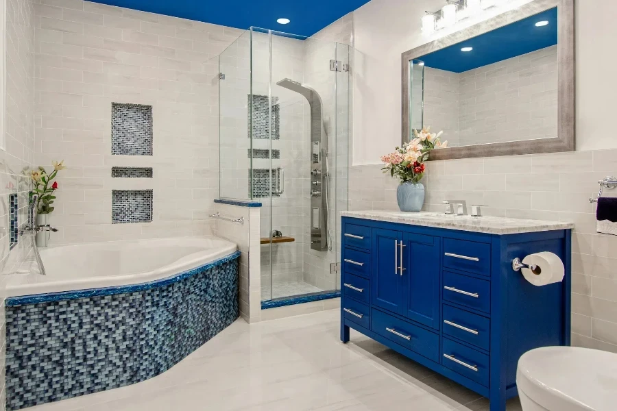 A white tiled bathroom with blue cabinets