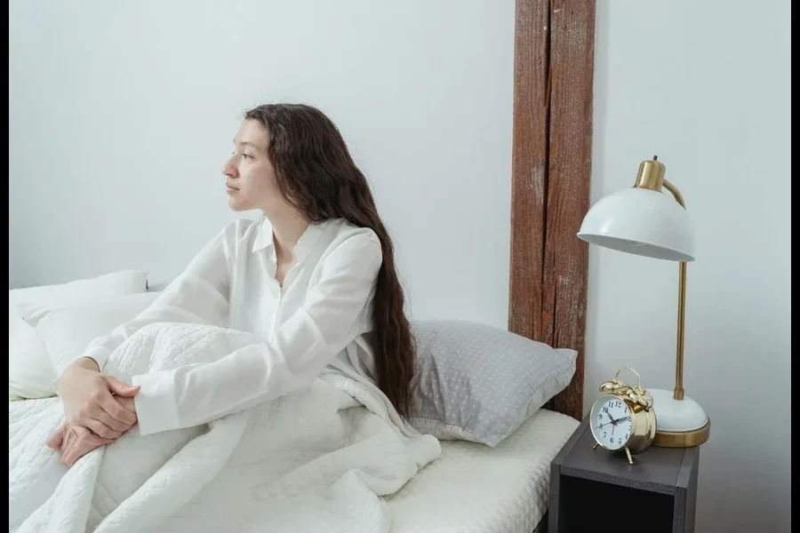 A woman sitting on the bed and staring outside