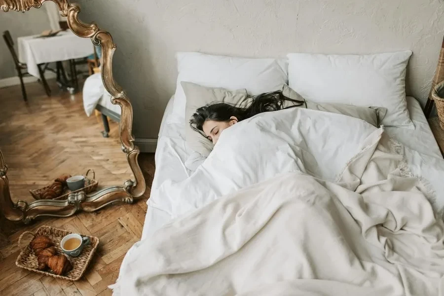 A woman sleeping with tea beside the bed