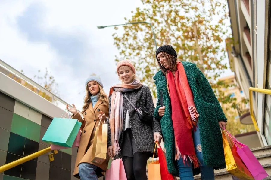 Happy women in wool coats strolling through city