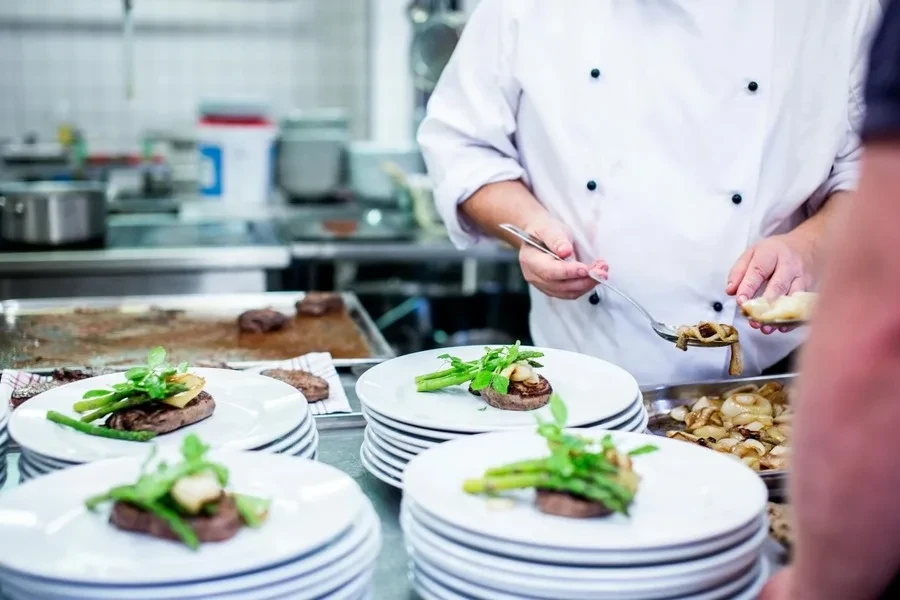 Man in white top standing beside plates