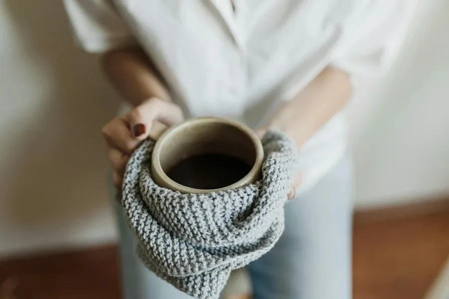 Woman holding ceramic cup with a kitchen towel