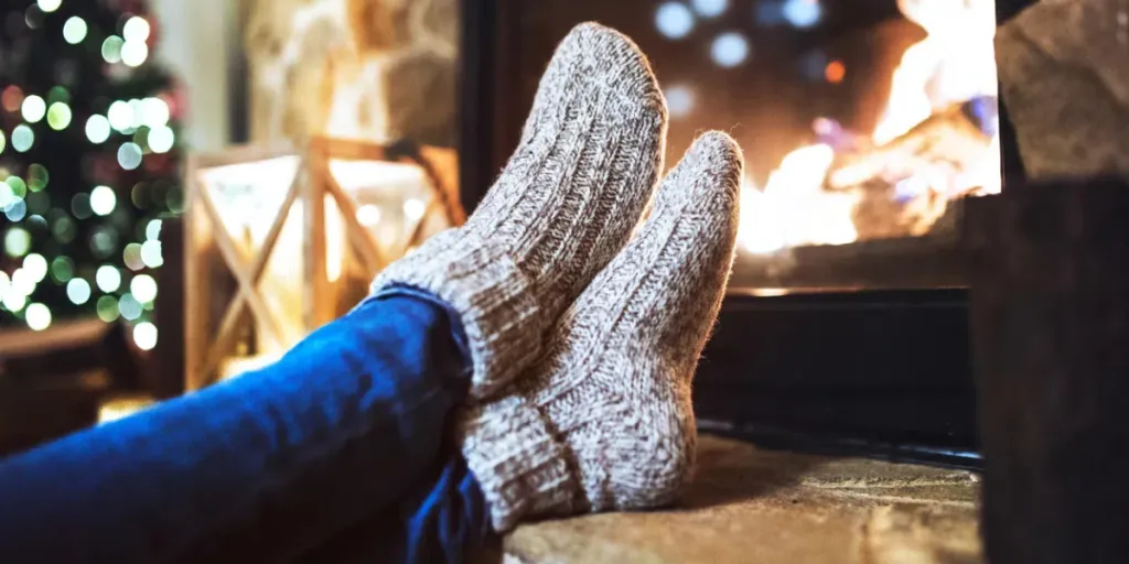 Woman in warm winter socks sitting in front of the fireplace