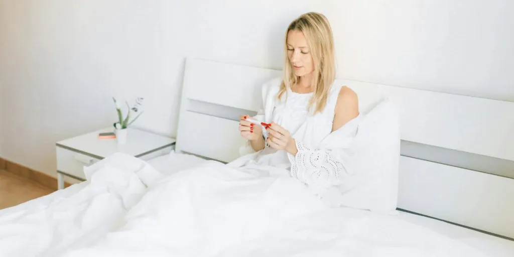 Woman in white sitting on a bed