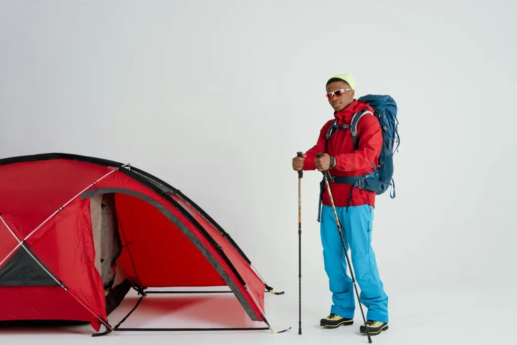 Young man ready for a winter camping adventure with a tent and hiking gear