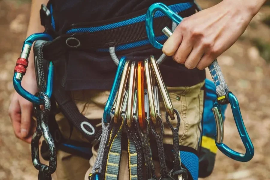Close-up of female rock climber wearing safety harness with quickdraws and climbing equipment outdoor