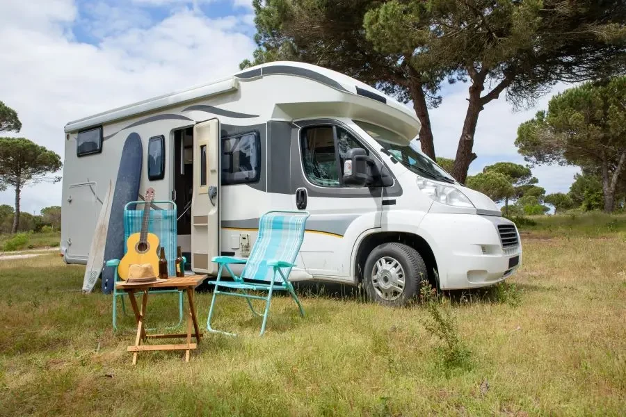 Explore the outdoor lifestyle with an RV, surfboards, and guitar in a serene Portuguese park