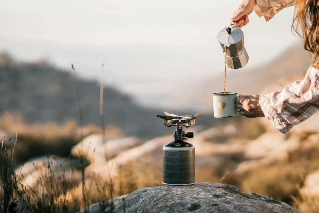 A serene scene of coffee being poured at a campsite, evoking morning tranquility