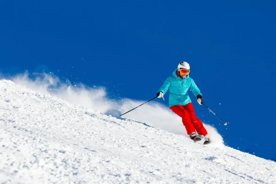 Dynamic shot of a woman skiing downhill on a bright winter day, perfect for skiing fun