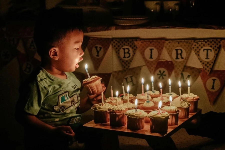 A child blowing out candles on cupcakes