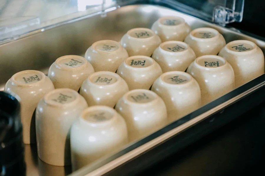 A group of white cups in a metal tray