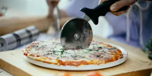 A person cutting a pizza