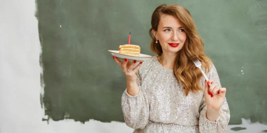 A person holding a plate of cake and fork