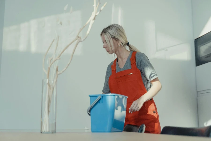 A person in an orange overalls and a bucket