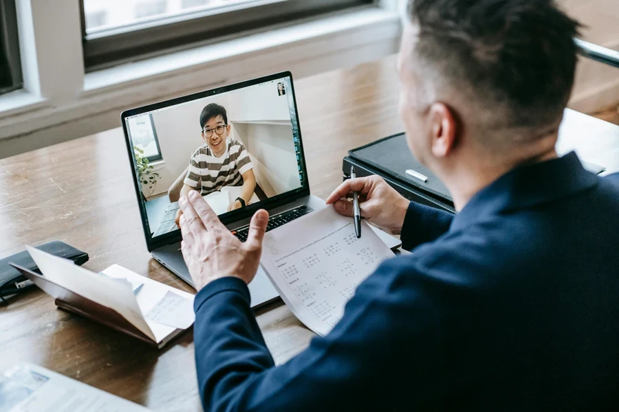 A professional having a video conference on a laptop from a home office, engaging in online communication