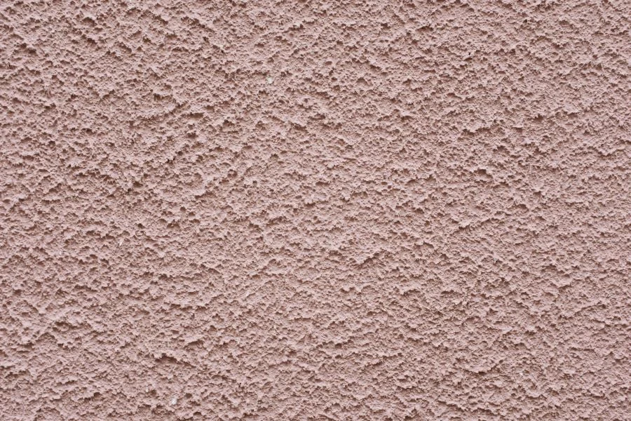 A textured wall with pink paint