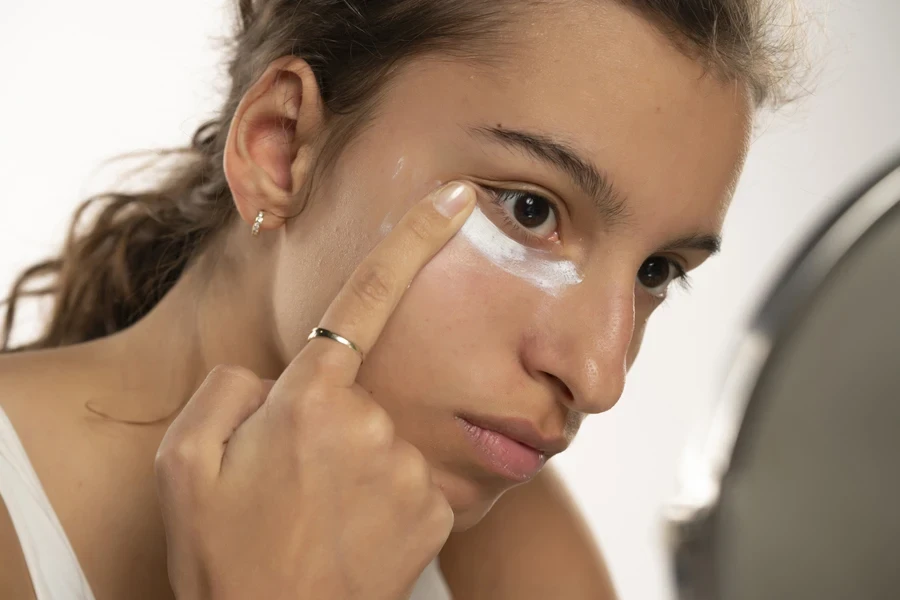 A young woman applying eye cream