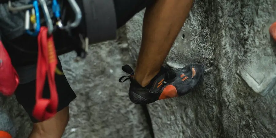 An athlete demonstrating precise footwork and equipment use in an indoor rock climbing setting