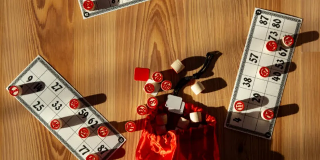 Bingo cards and bingo chips on table with red bag