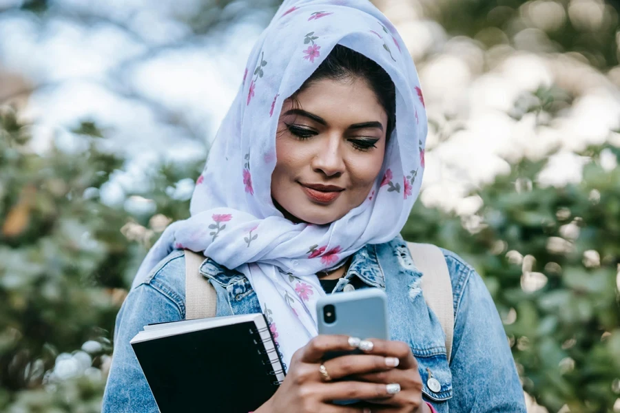 Cheerful Muslim woman with smartphone