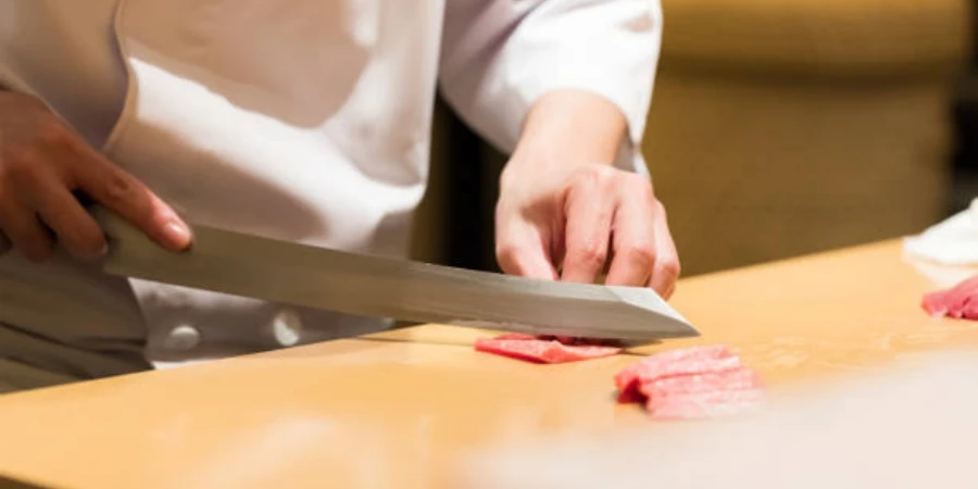 Chef Cook Making Sushi Sashimi with Sharp Knife on the Cutting Board