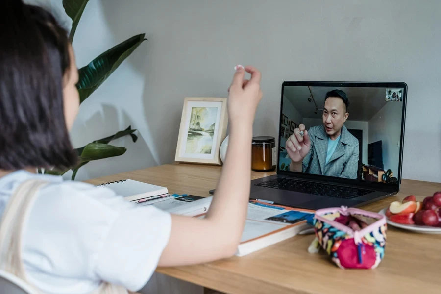 Child attends an online class with a teacher via video call on a laptop