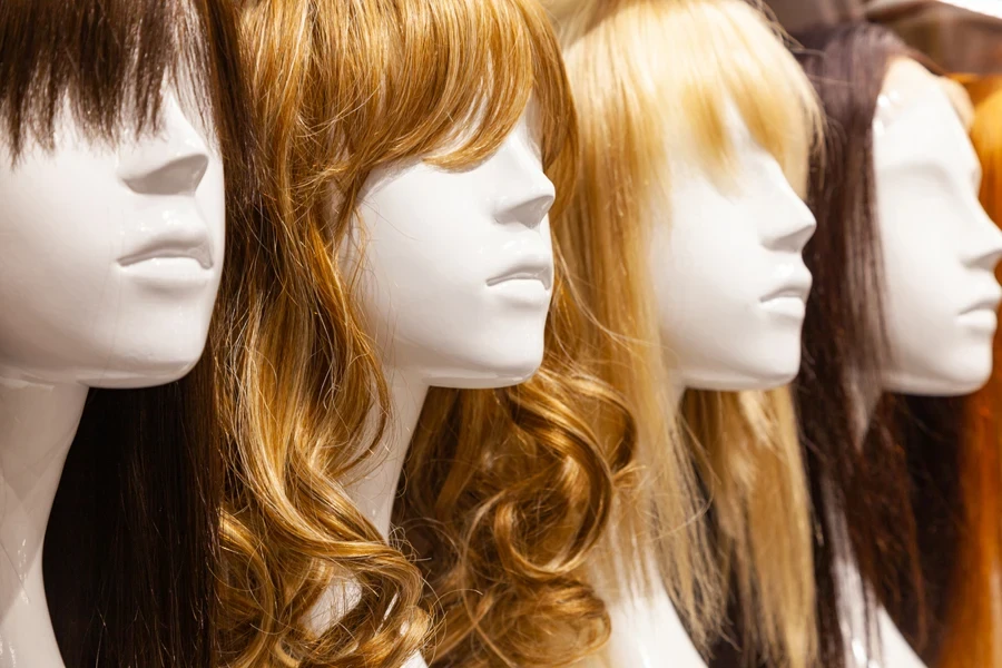 Four wigs on white mannequin heads with different lengths