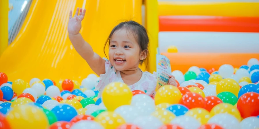 Menina com o braço levantado em balões coloridos