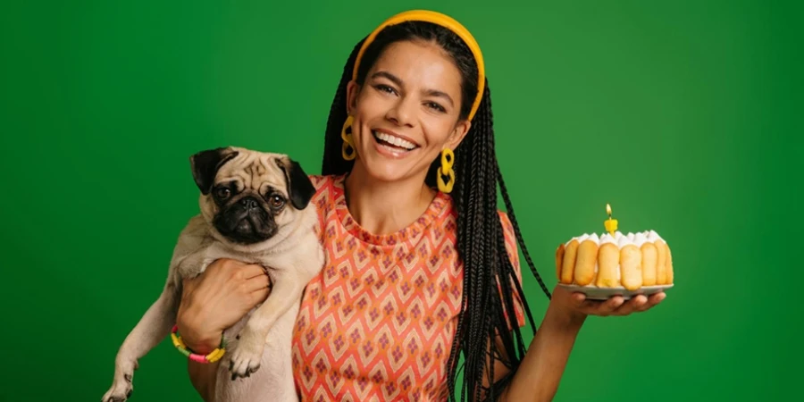 Happy Young Hispanic Woman Carrying Cute Pug Dog and Birthday Cake