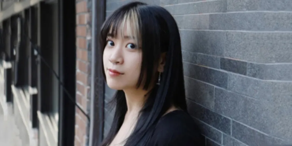 Japanese woman with hime cut standing against brick wall