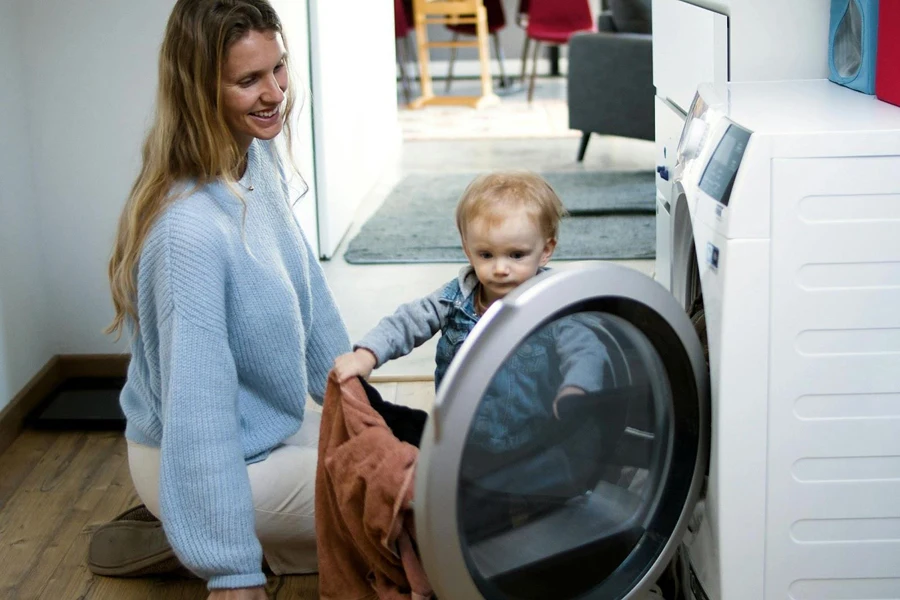 Kid and mum loading clothing in a front-load washer