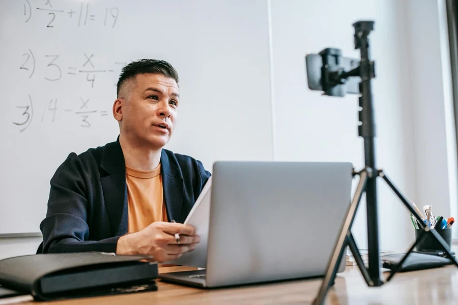 Male instructor conducting an online education session with a laptop and camera