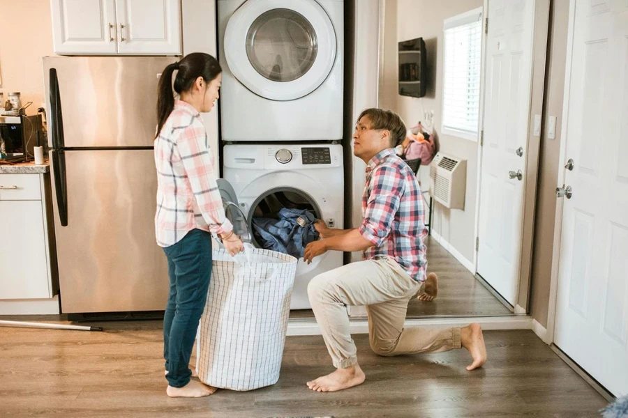 Man and woman loading clothes into a washer-dryer combo