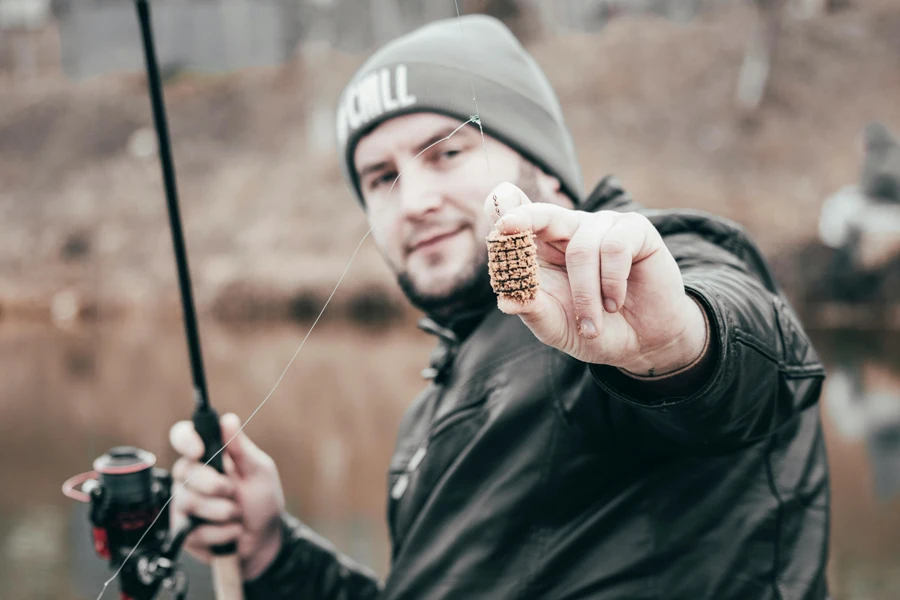 Uomo in giacca nera che tiene un'esca da pesca