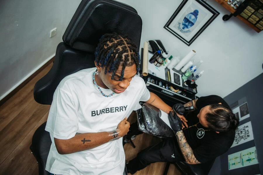 Man with a braided hairstyle getting a tattoo